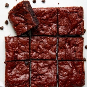 Red Velvet Brownies cut into squares on a white table with one brownie on its side from overhead.