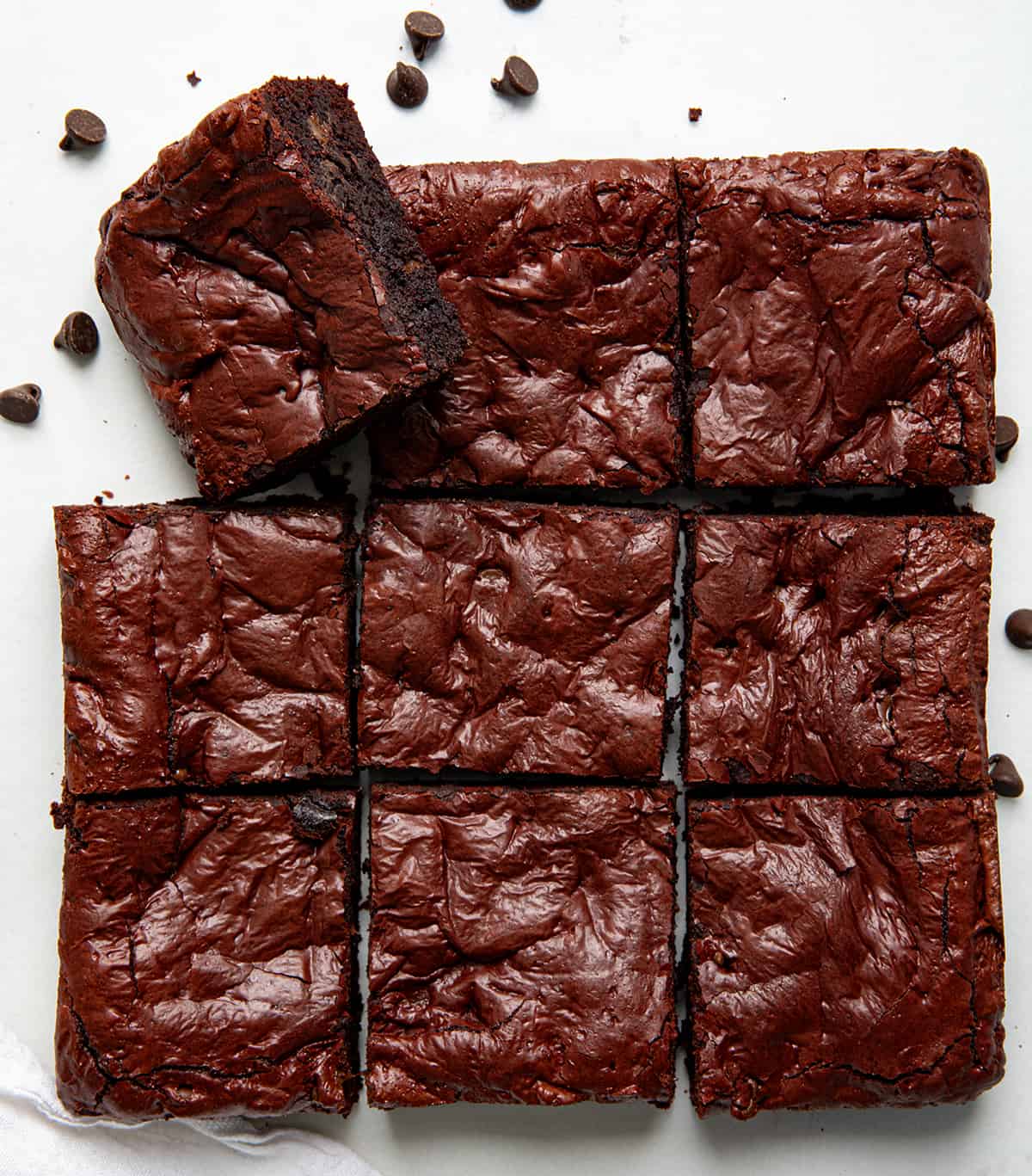 Red Velvet Brownies cut into squares on a white table with one brownie on its side from overhead.