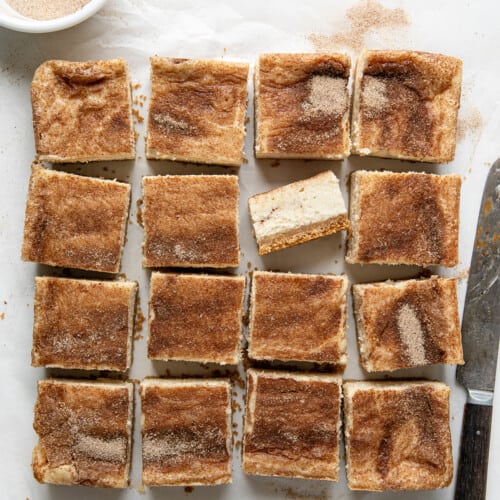 Snickerdoodle Cheesecake Bars cut into squares and one bar flipped on it's side.