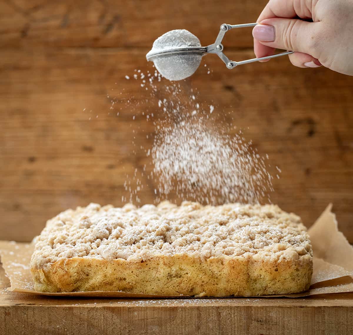 Dusting the top of a Banana Crumb Cake with confectioners sugar.