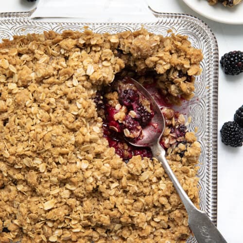 Pan of Blackberry Crisp with a scoop removed showing hot blackberries from overhead.