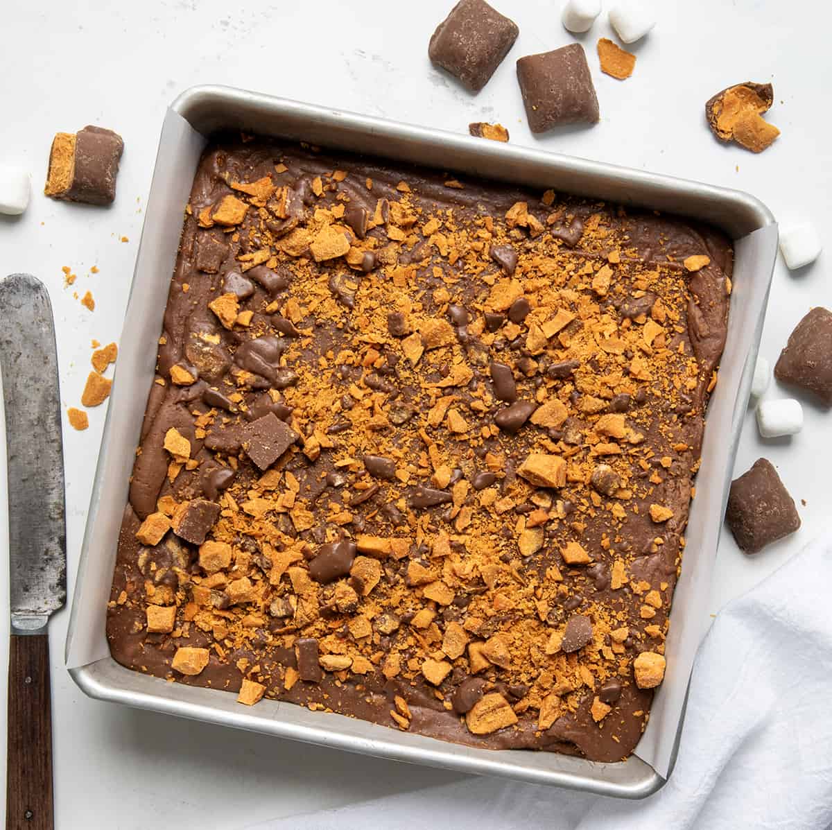 Pan of Butterfinger Fudge on a counter surrounded by butterfingers and a knife from overhead.