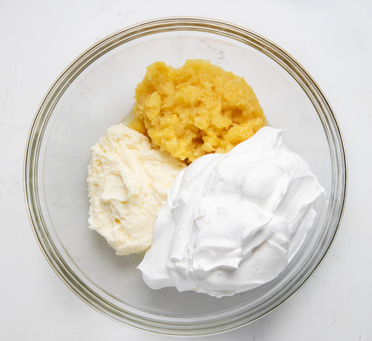 Glass bowl of ingredients used to make Pineapple Pretzel Fluff.