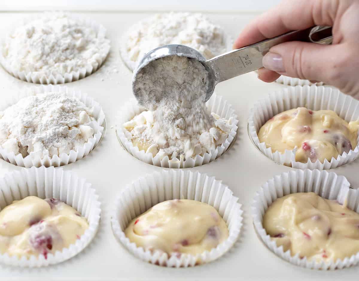 Raw Raspberry Muffin batter in pan and adding crumb topping.