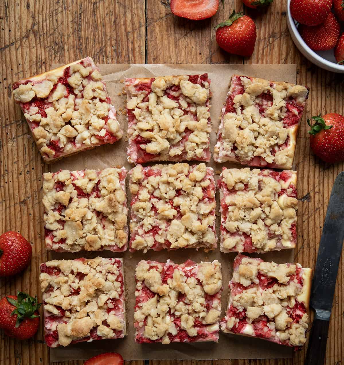 Strawberry Cheesecake Bars cut into squares on a wooden table from overhead. 