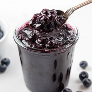 Jar of Blueberry Jam that doesn't use pectin with a spoon picking up a big portion.