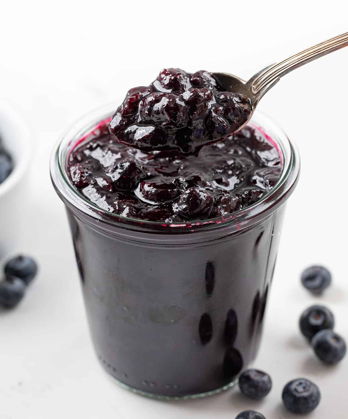 Jar of Blueberry Jam that doesn't use pectin with a spoon picking up a big portion.