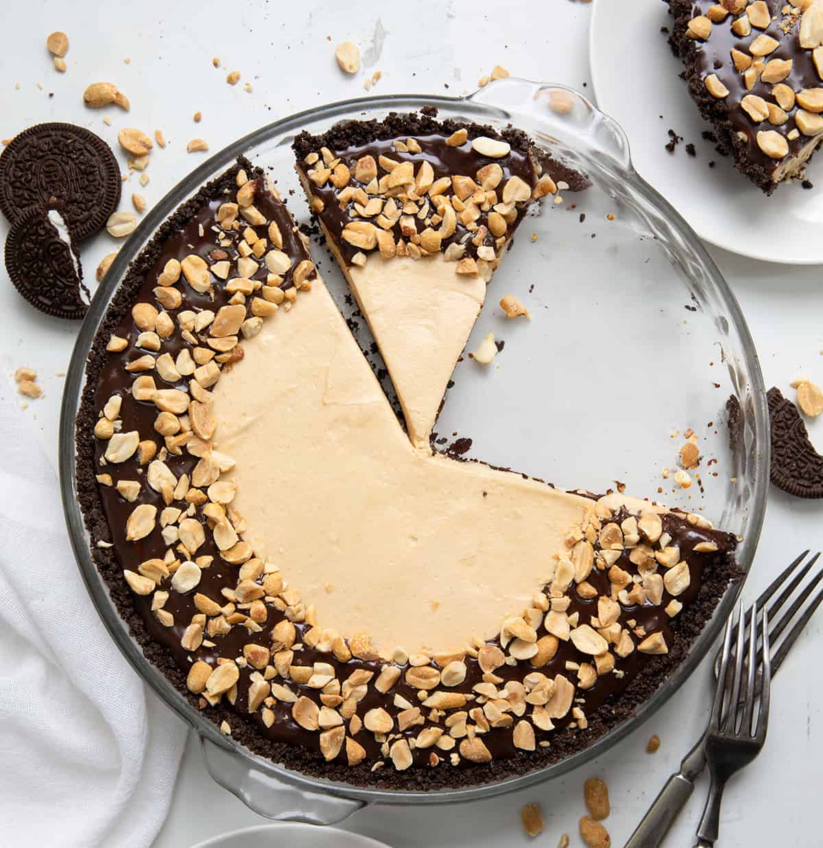 a No Bake Buckeye Cheesecake on a white counter with a couple of pieces removed.