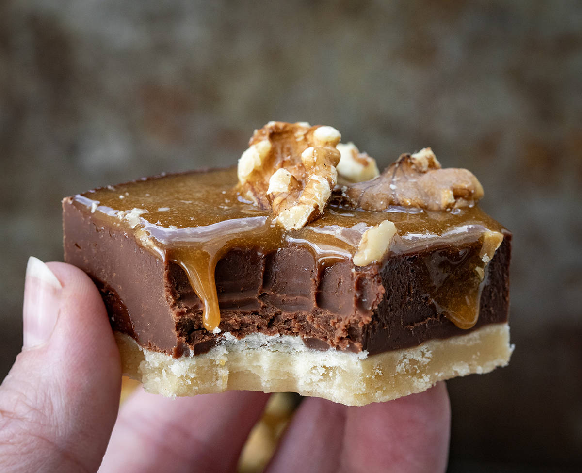 Hand holding a Salted Caramel Fudge Bar with caramel dripping down.