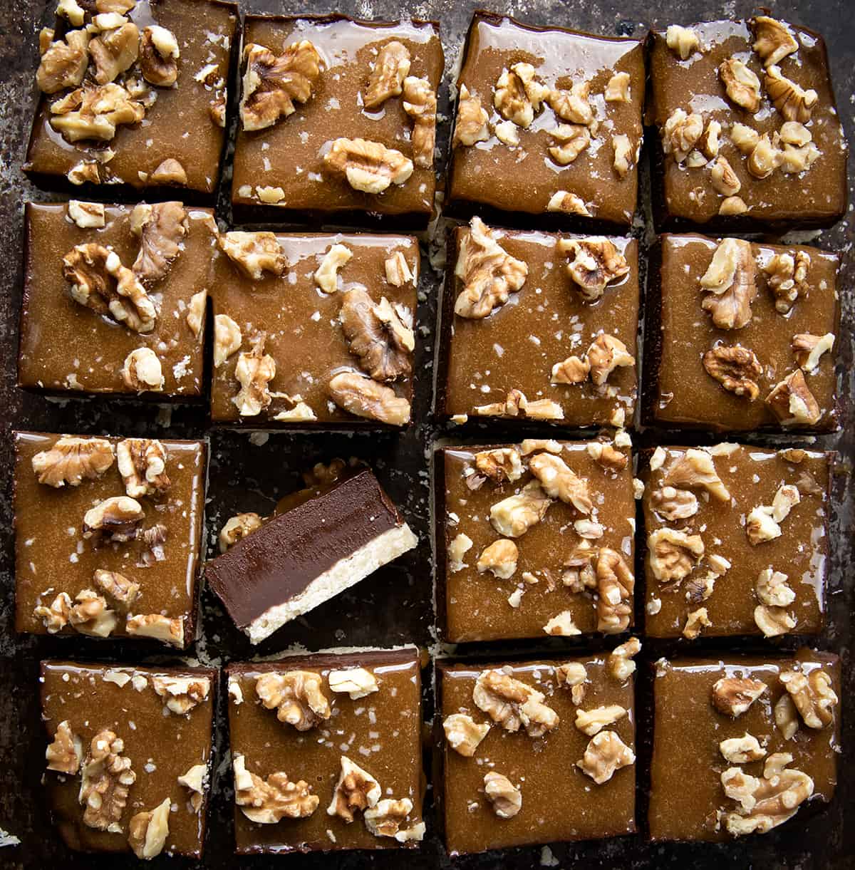 Salted Caramel Fudge Bars on a table all cut up into pieces with one bar on its side. 