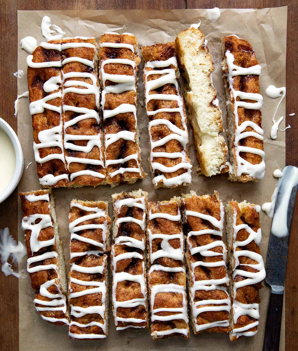 Cinnamon Roll Focaccia sticks on a piece of brown parchment paper from overhead on a wooden table.
