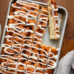 Pan of Cinnamon Roll Focaccia cut into sticks with one on its side.