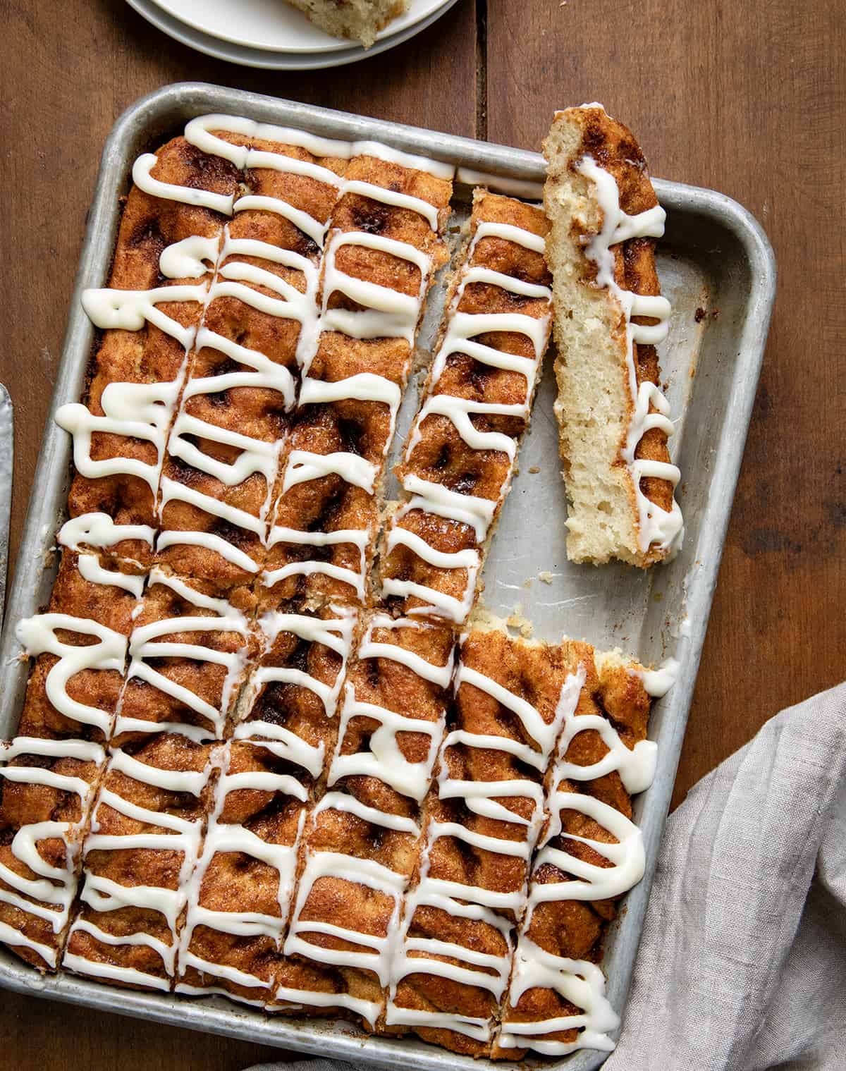 Pan of Cinnamon Roll Focaccia cut into sticks with one on its side. 