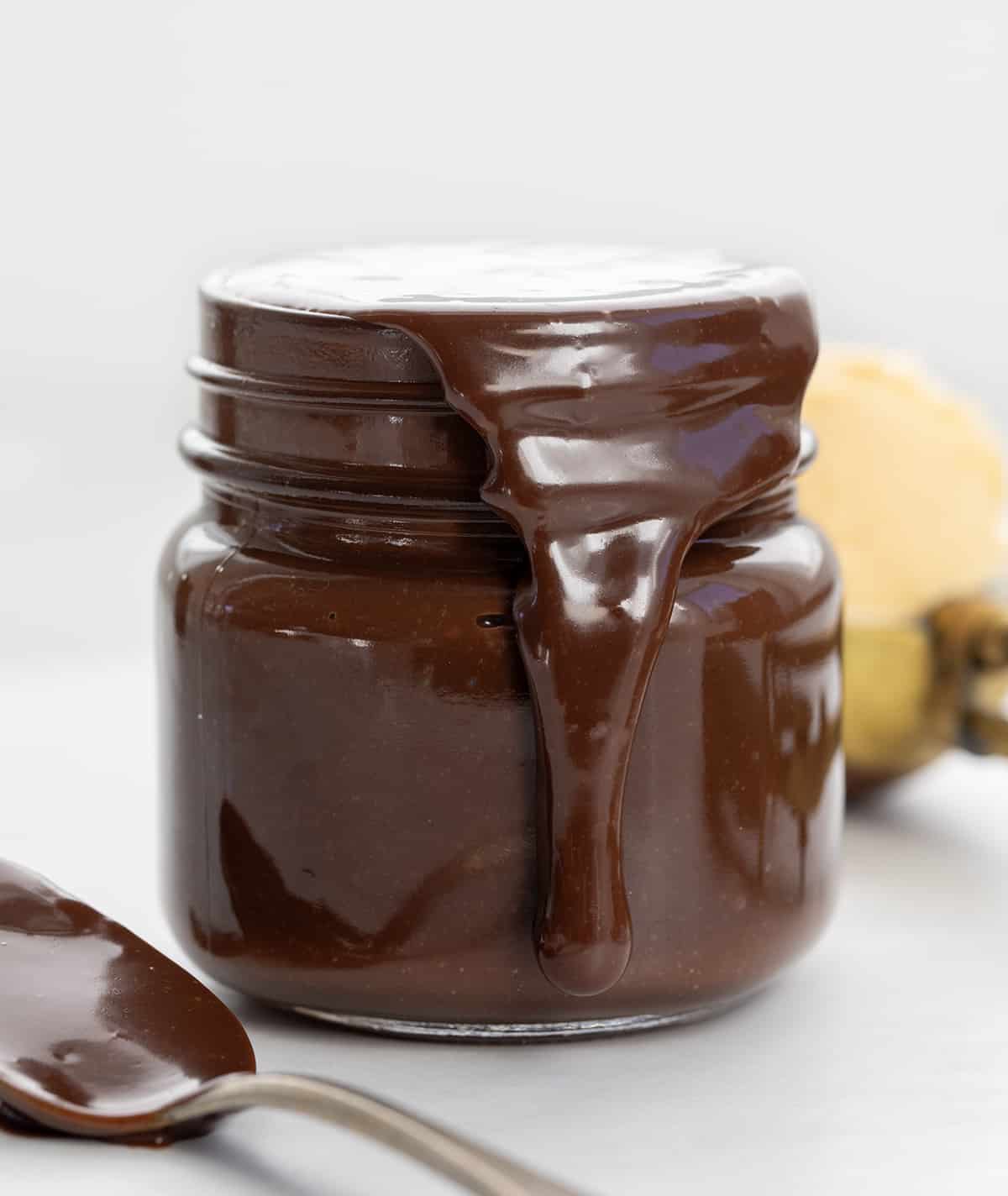 Jar of Salted Hot Fudge overflowing and dripping down side. 
