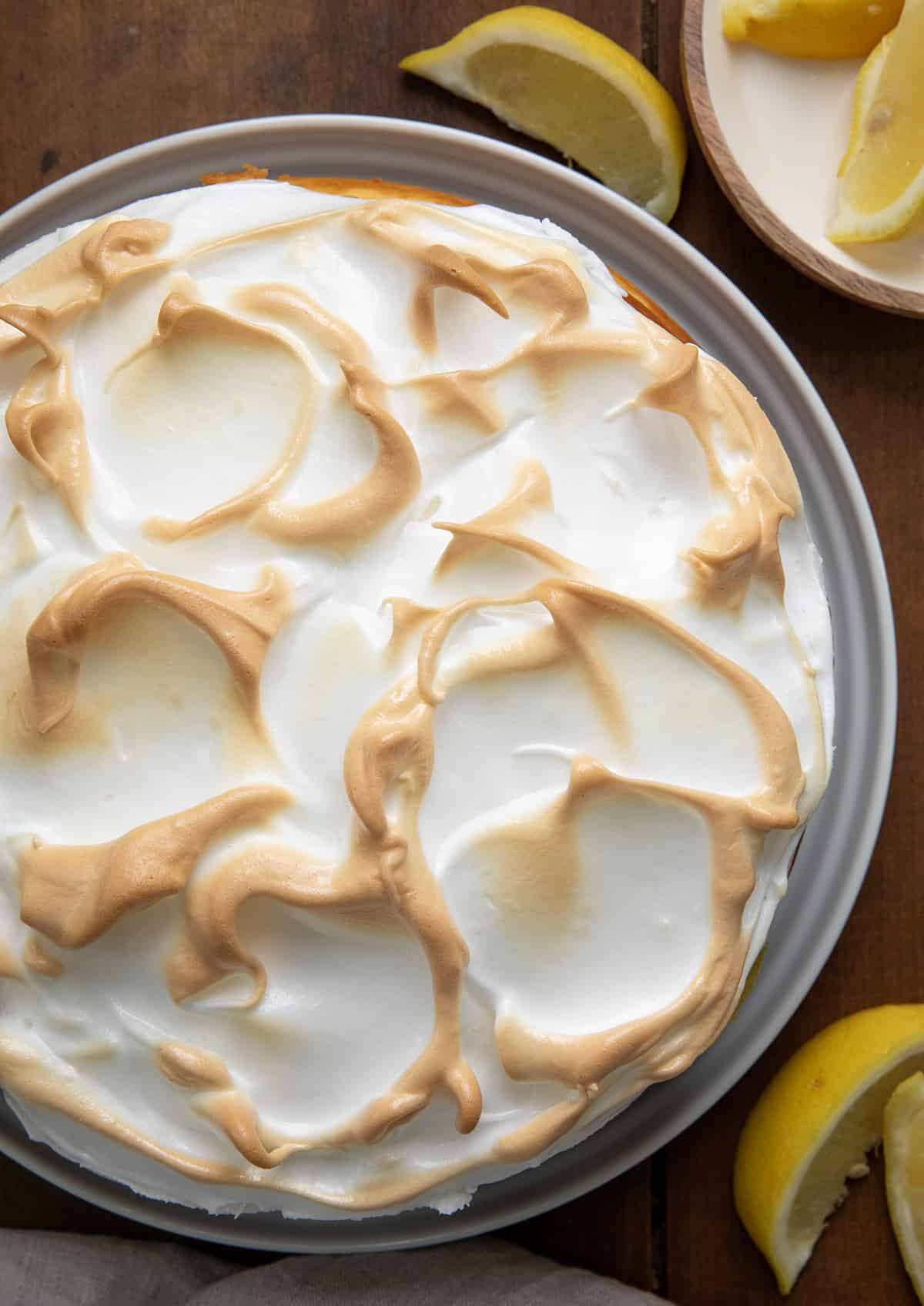Whole Lemon Meringue Cheesecake on a wooden table from overhead. 