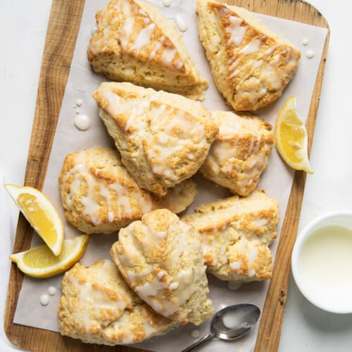 Lemon Scones on a cutting board on a white table with lemons from overhead.