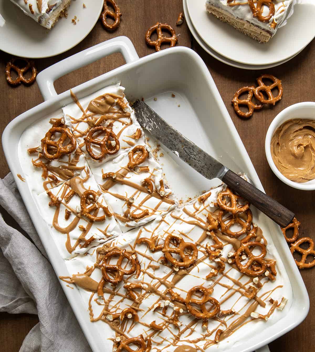 Pan of Peanut Butter Pretzel Dessert with a couple of pieces removed on a wooden table from overhead. 