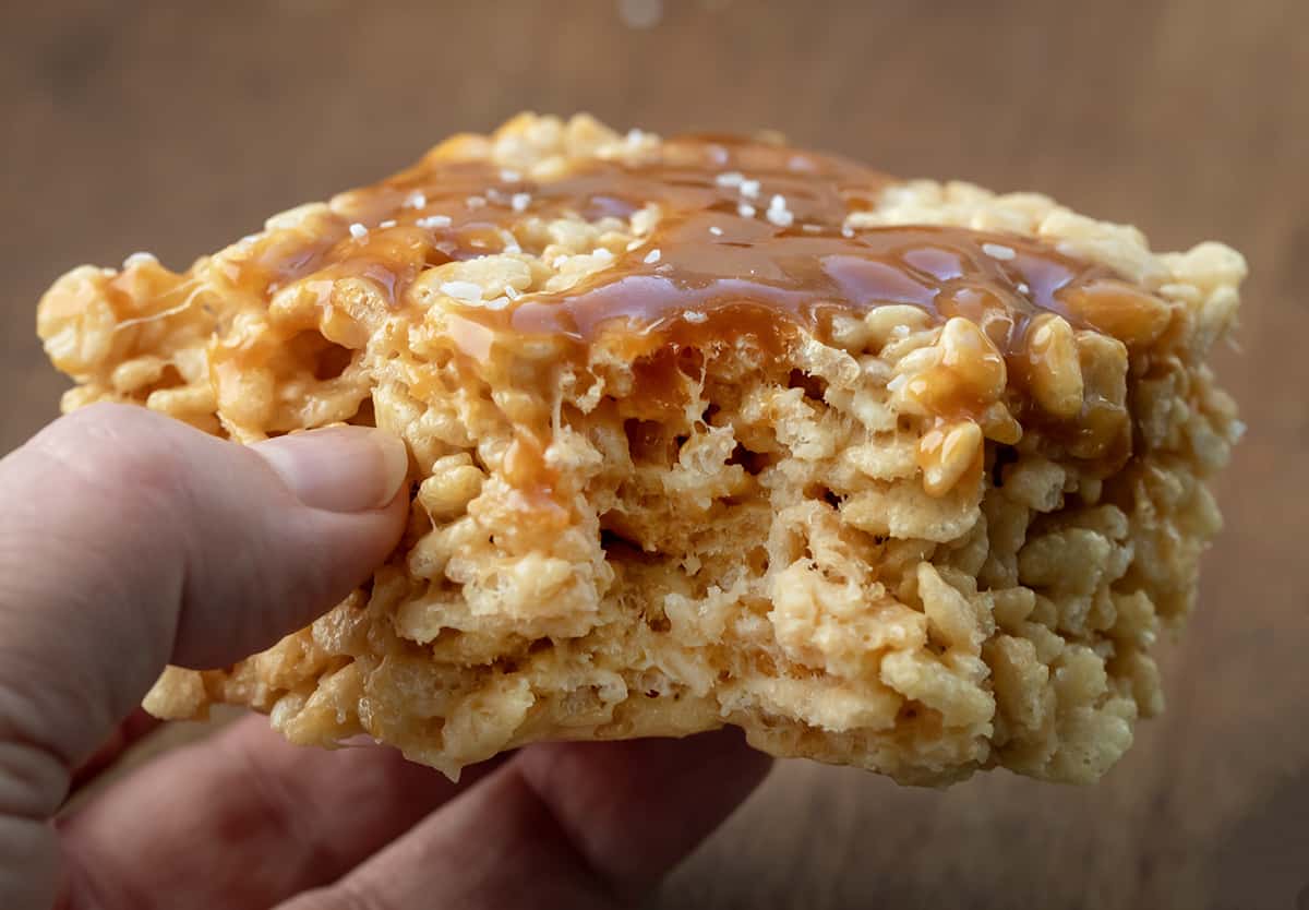 Hand holding a Salted Caramel Rice Krispie Treat with a bite removed.