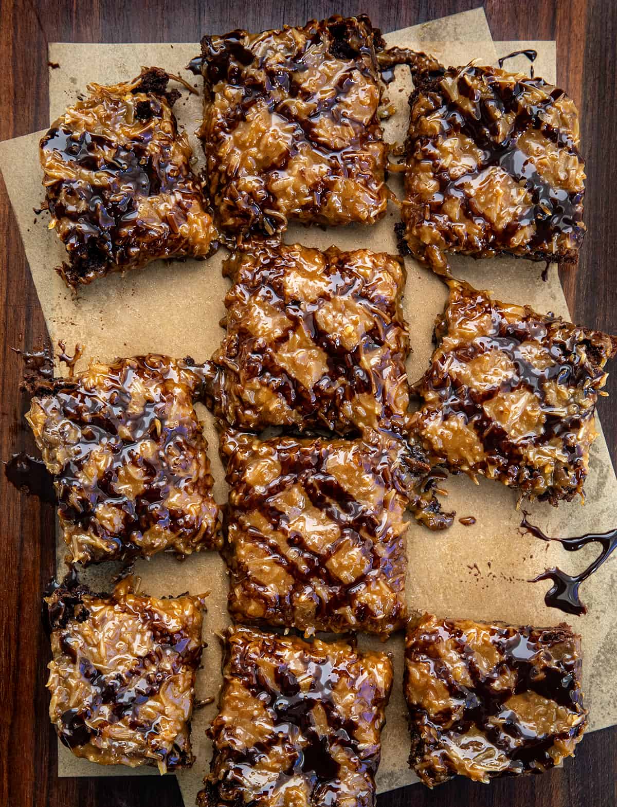 Toasted Coconut Brownies on parchment paper on a wooden table from overhead and cut into pieces.