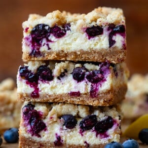 Stack of Blueberry Lemon Cheesecake Bars on a wooden table.