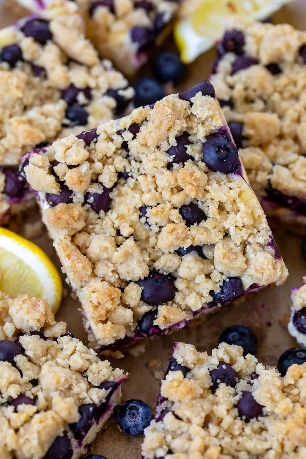 Close up of Blueberry Lemon Cheesecake Bars all stacked together on a wooden table.