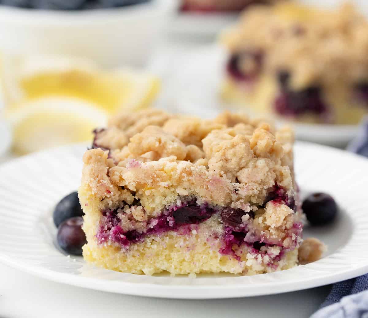 Piece of Blueberry Lemon Crumb Cake on a white plate showing crumb and blueberries.