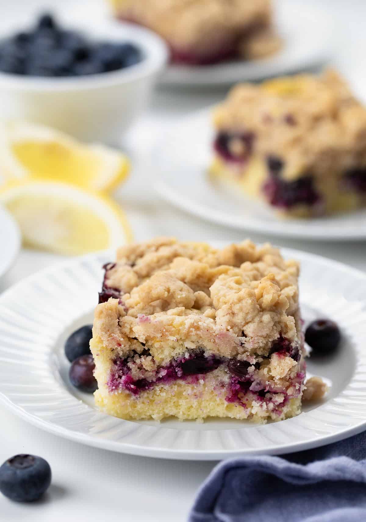 Piece of Blueberry Lemon Crumb Cake on a white plate showing crumb and blueberries.