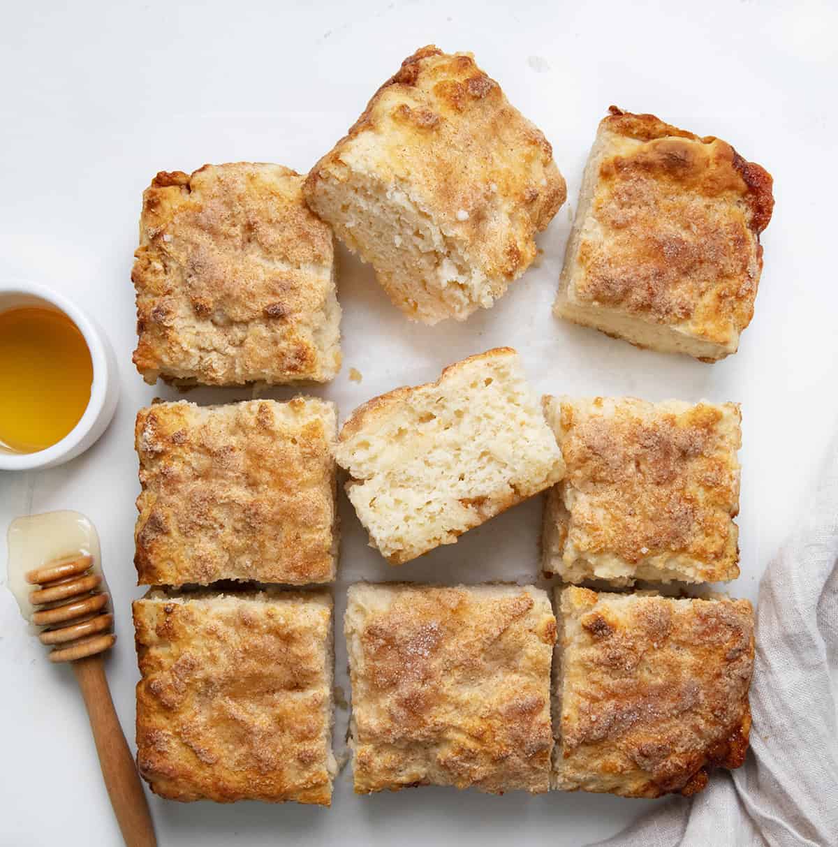 Cinnamon Honey Butter Swim Biscuits on a white table cut into squares.