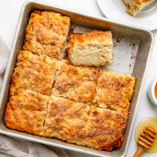 Cinnamon Honey Butter Swim Biscuits in the pan with one removed and one on its side.