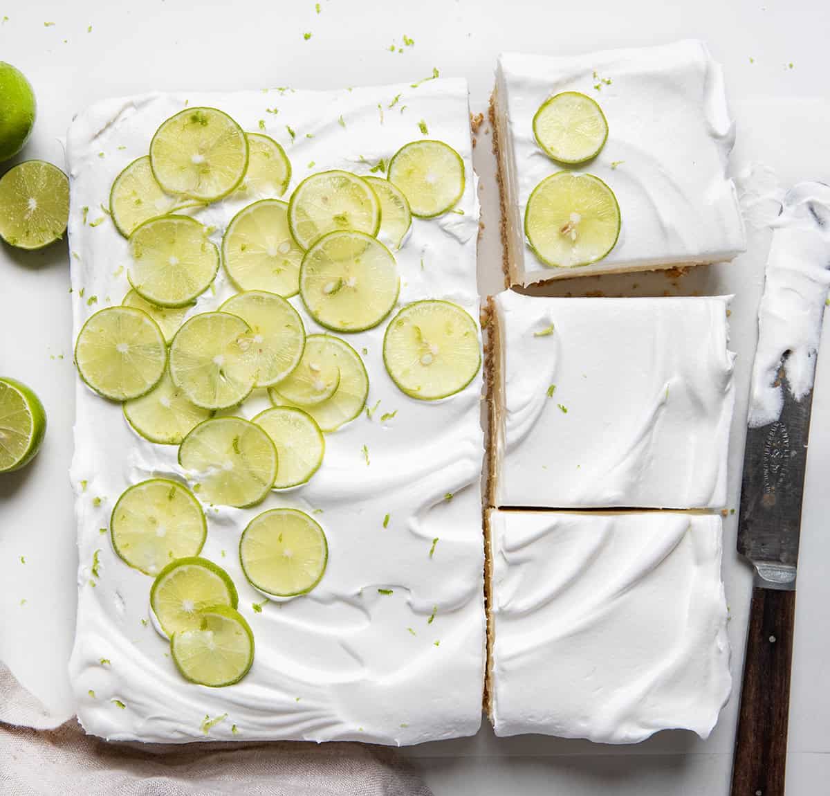 Key Lime Pie Bars on a white table with some bars cut from overhead.