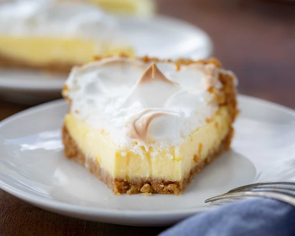 Piece of Magic Lemon Pie on a white plate with one bite removed.