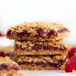 Stack of Raspberry Oatmeal Crumble Bars on a white table.