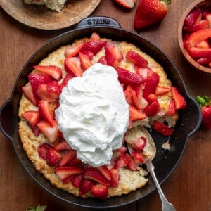 Skillet Strawberry Shortcake with some removed on a wooden table from overhead.