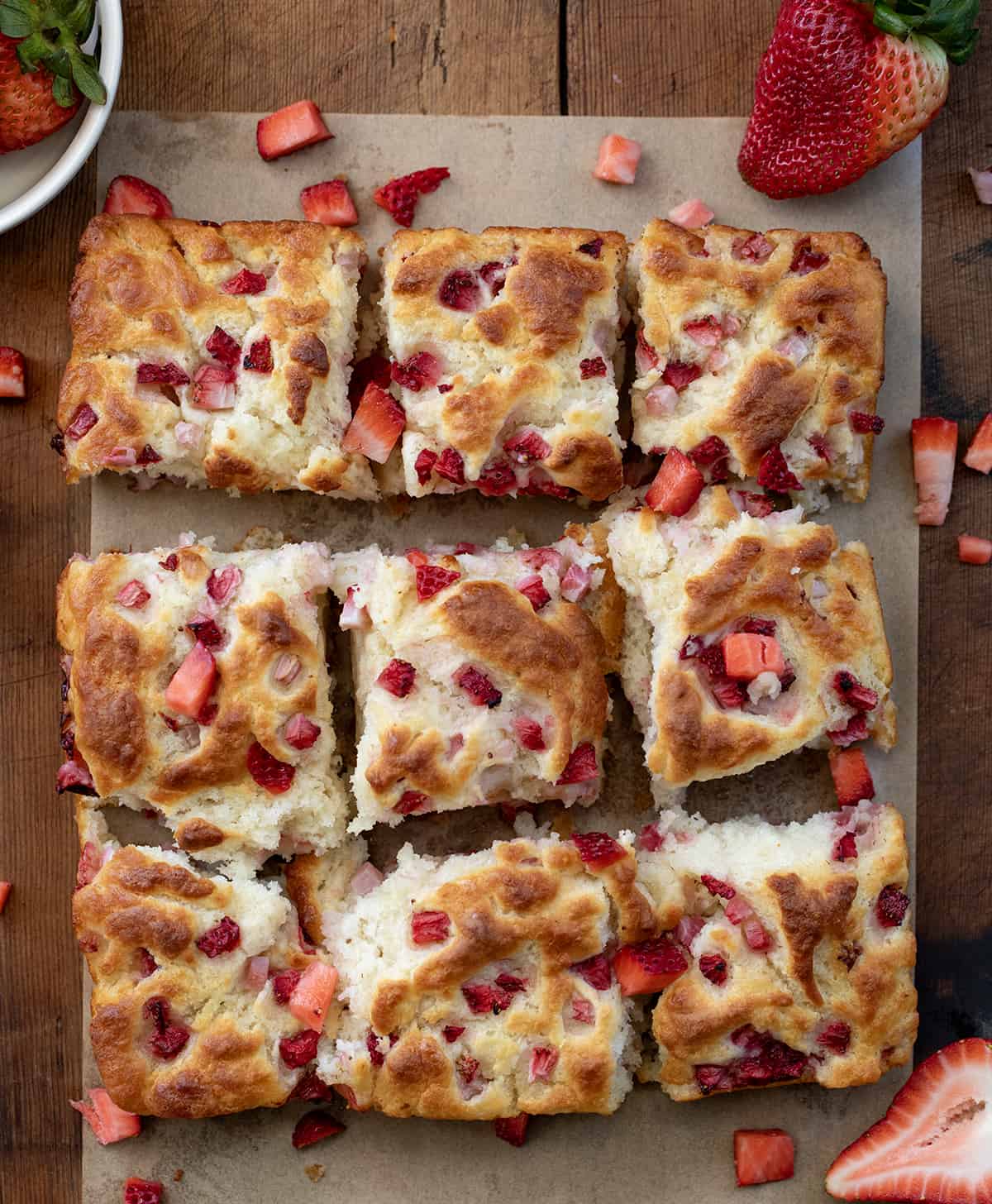 Strawberry Butter Swim Biscuits on a wooden table separated into pieces from overhead.