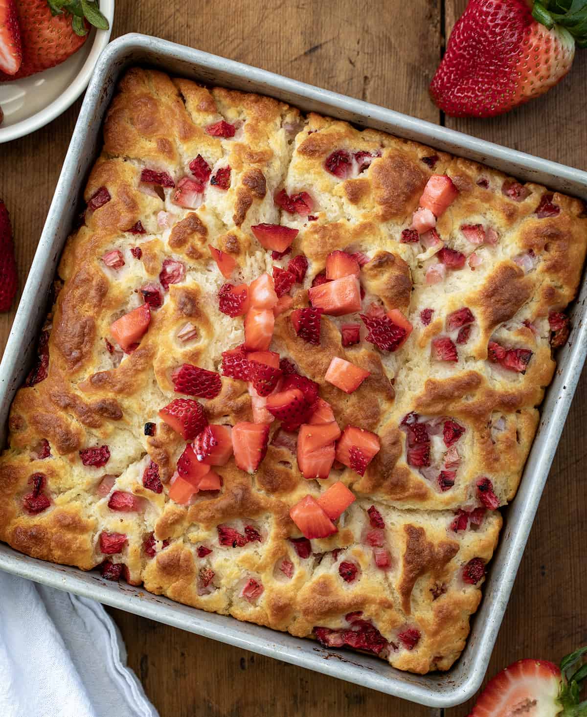 Strawberry Butter Swim Biscuits in a pan on a wooden table from overhead. 