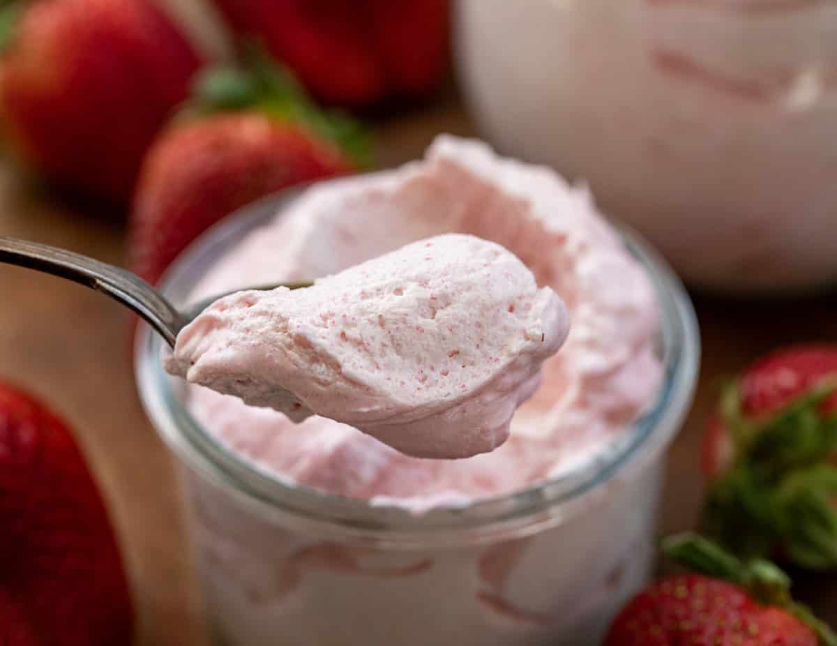 Spoonful of Strawberry Cheesecake Mousse being held in front of the jar.