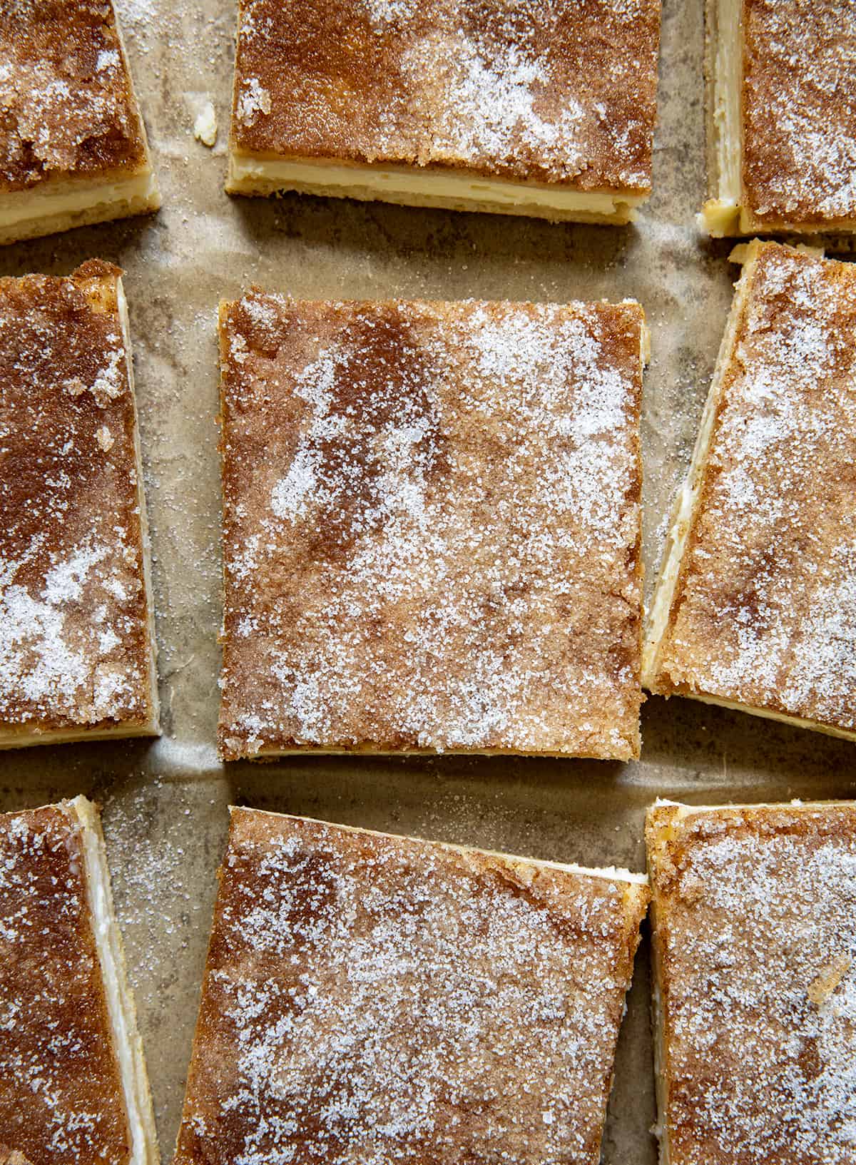 Close up of Churro Cheesecake Bars on a piece of parchment paper from overhead.