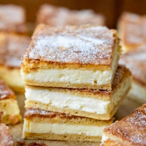 Stack of Churro Cheesecake Bars surrounded by more bars on a wooden table.