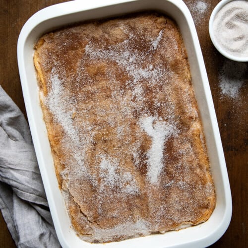 Churro Cheesecake Bars in a baking dish on a wooden table from overhead.