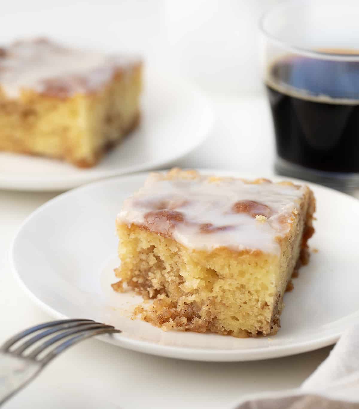 Piece of Honey Bun Cake on a white plate with a bite removed.