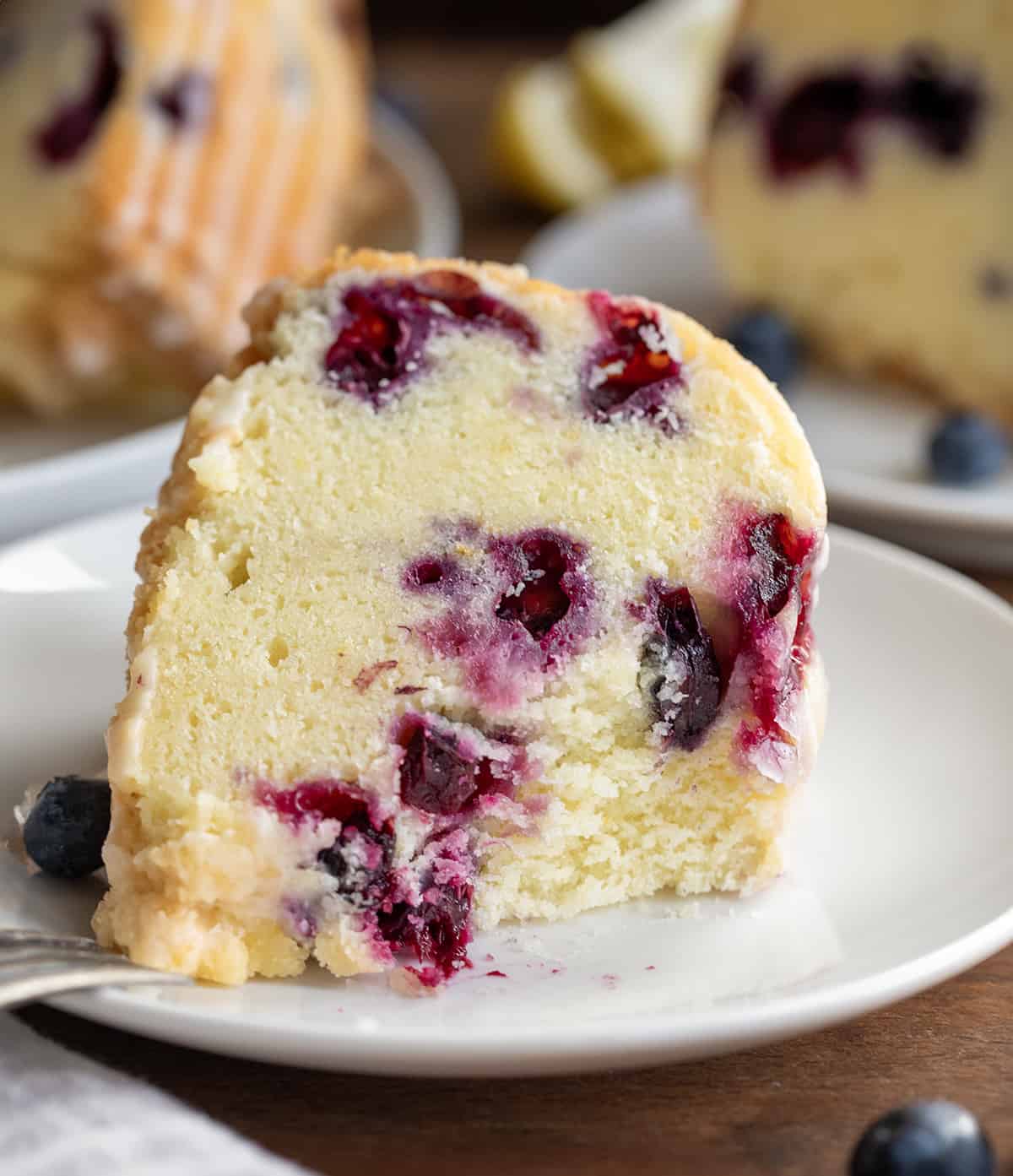 Piece of Lemon Blueberry Pound Cake on its side with a bite removed showing inside texture of cake.