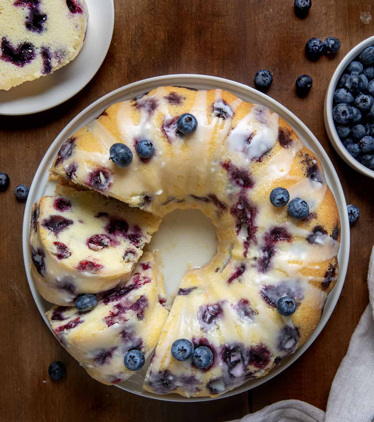 Lemon Blueberry Pound Cake on a wooden table from overhead with a few pieces cut and falling on their side. 