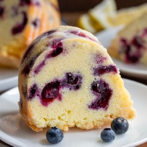 Piece of Lemon Blueberry Pound Cake on a white plate with fresh blueberries.
