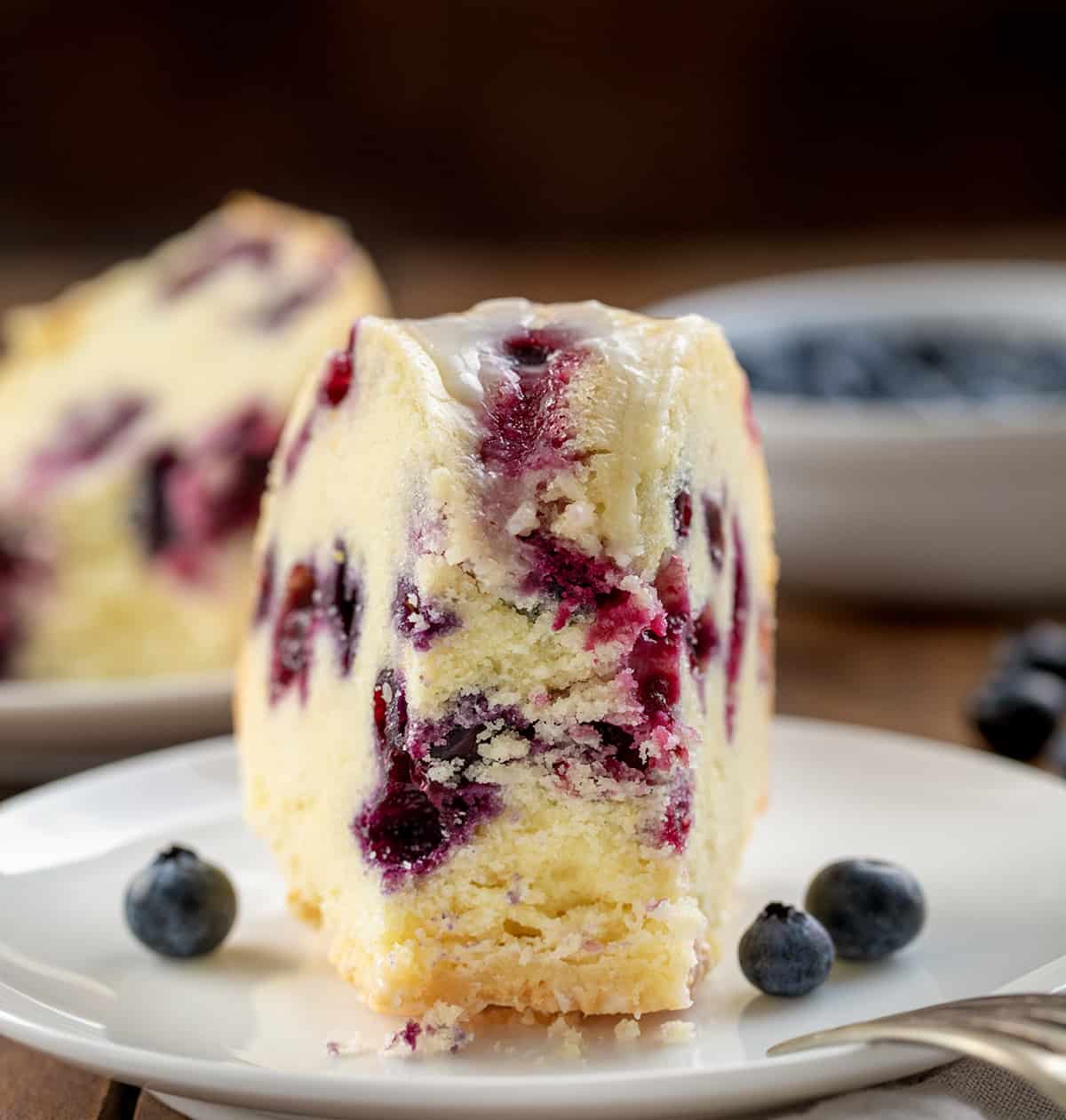 Piece of Lemon Blueberry Pound Cake with some of the cake removed on a white plate.