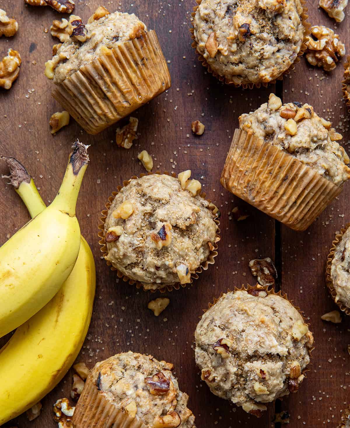 Banana Nut Muffins on a wooden table with bananas from overhead.