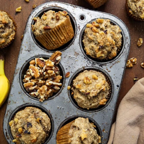 Banana Nut Muffins in a pan on a wooden table from overhead.