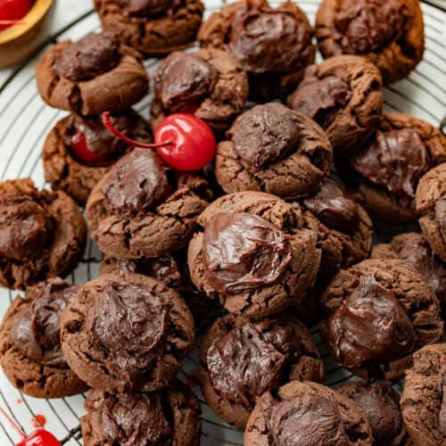 Chocolate Covered Cherry Cookies on a cooling rack with cherries around.