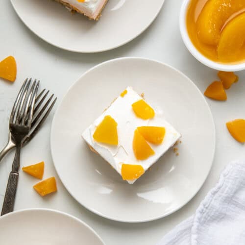 Pieces of Peach Delight on white plates on a white table from overhead.