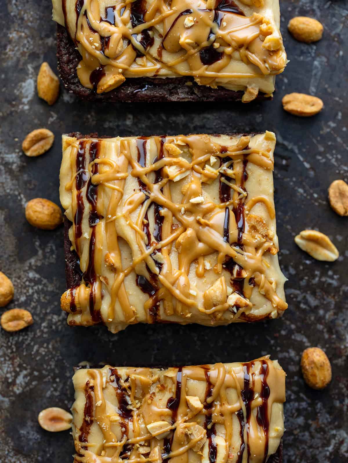 Three Peanut Butter Mousse Brownies on a baking sheet with peanuts around.