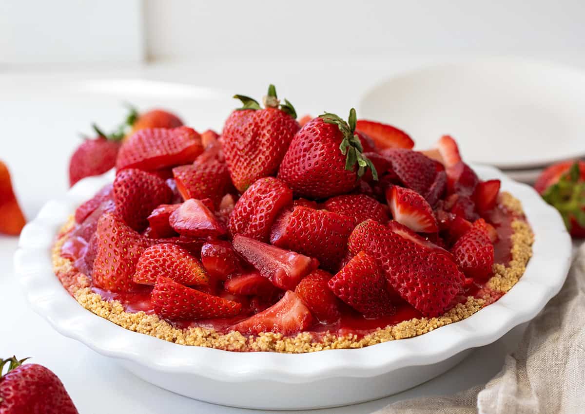 Whole Strawberry Cream Cheese Pie in a white pie plate on a white counter.